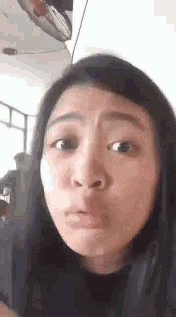 a young woman is making a funny face while looking at the camera .