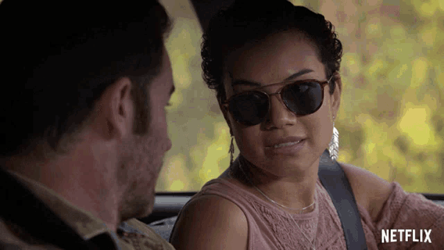 a woman wearing sunglasses sits in a car next to a man with the word netflix on the bottom