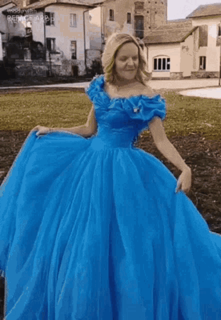 a woman in a blue dress is standing in a grassy field .