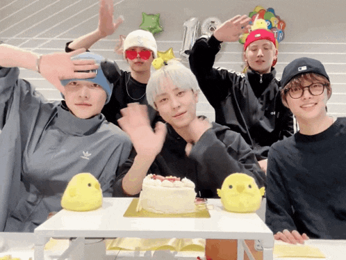 a group of young men are posing for a picture in front of a cake and stuffed ducks