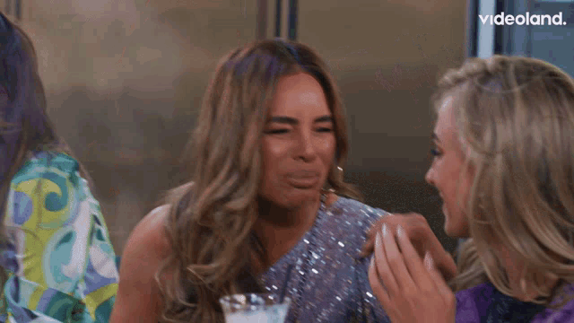 two women laughing in front of a videoland advertisement