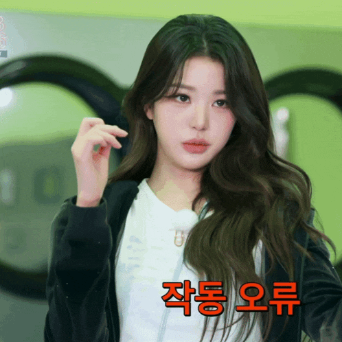a woman in a black jacket stands in front of a laundromat machine with korean writing on the bottom