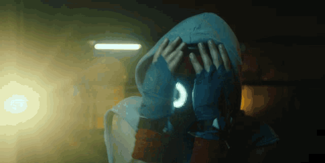 a person covering their face with their hands with a glowing s on their wrist