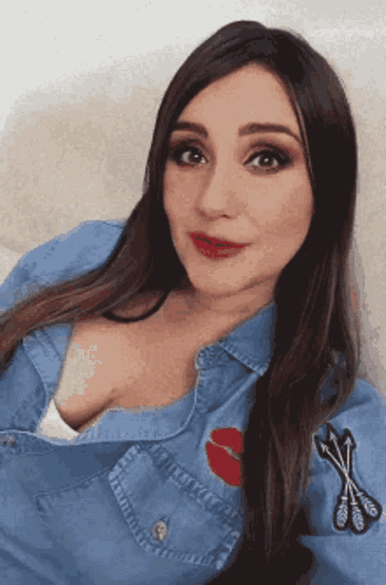 a woman wearing a blue denim shirt with a red lip on the chest