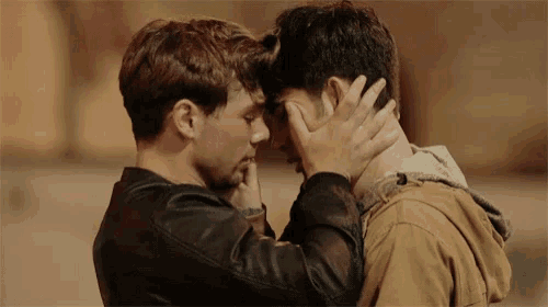 a couple of men are touching each other 's faces in a close up .