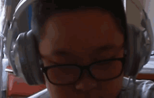a man wearing headphones and glasses looks down at something