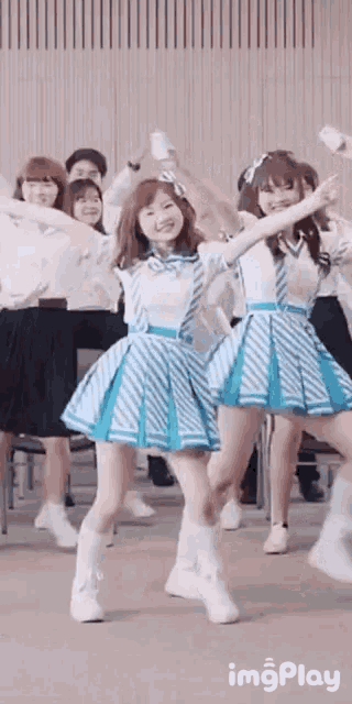 a group of girls are dancing together in a room with their arms in the air .