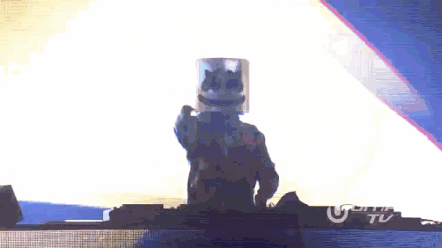 a dj with a marshmallow on his head is playing music on a stage with a sign that says ultra tv