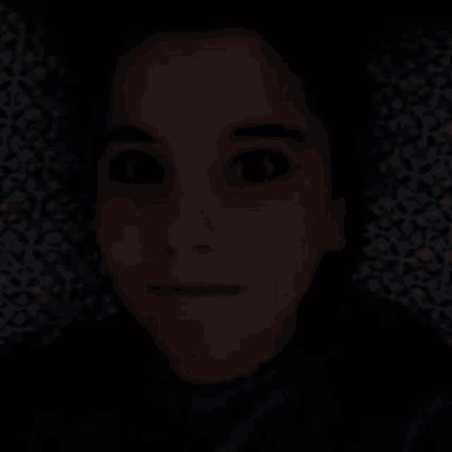 a close up of a person 's face in the dark with their eyes closed .