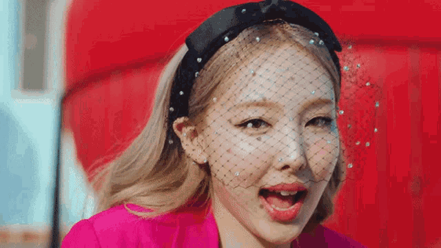 a woman with a veil on her face and a pink jacket