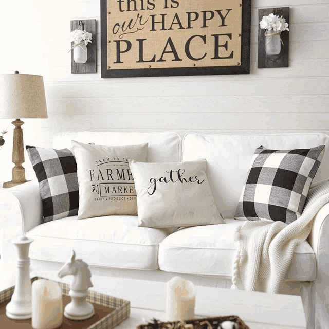 a white couch with black and white pillows and a sign that says this is our happy place