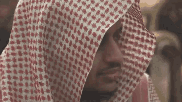 a close up of a man wearing a red and white checkered scarf around his head .