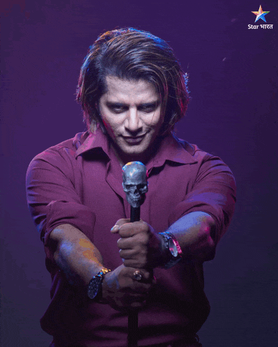 a man in a purple shirt is holding a microphone with a star in the background