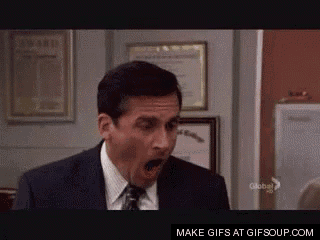 a man in a suit and tie is yawning with his mouth open in a room .