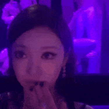 a woman is standing in front of a purple light and a purple light is behind her .