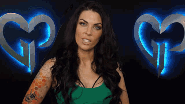 a woman with a tattoo on her arm stands in front of a heart