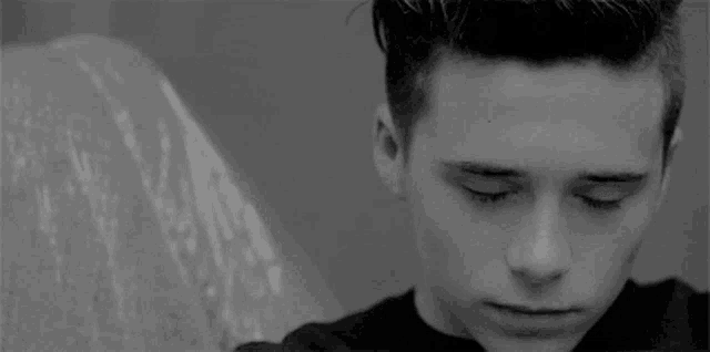 a black and white photo of a young man looking down .