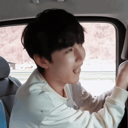 a young man sticking his tongue out in a car