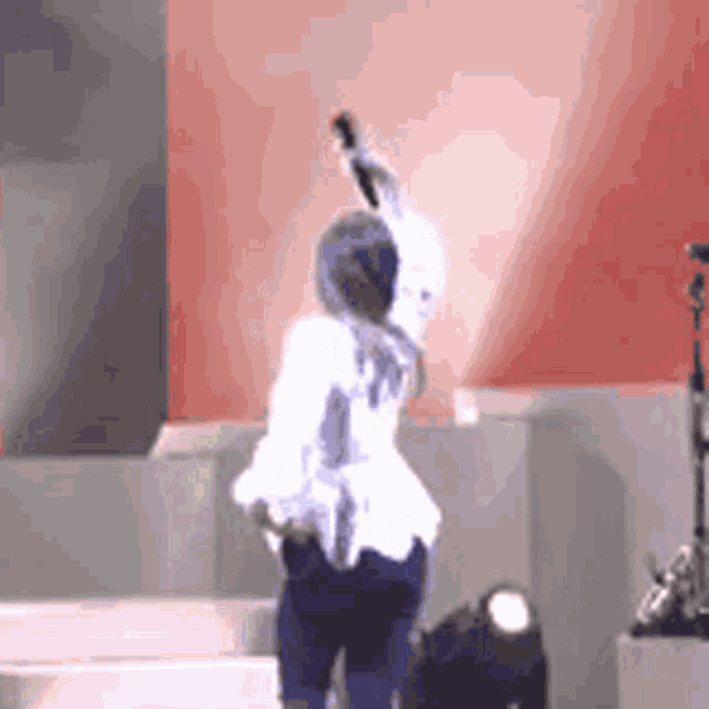 a woman is singing into a microphone while standing on a stage