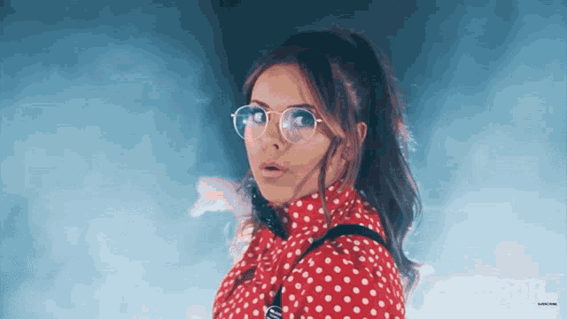 a woman wearing glasses and a red polka dot shirt is standing in front of a screen that says roh.com