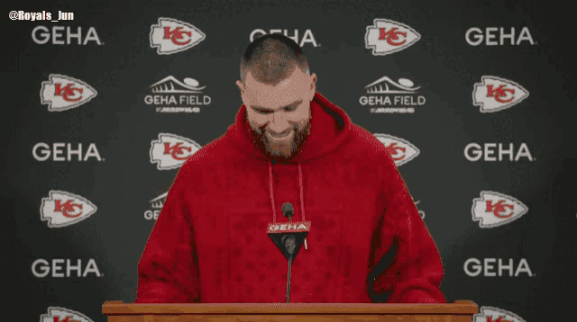 a man in a red hoodie stands in front of a podium and says do it do it