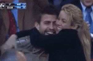a man and a woman are hugging in a crowd with a scoreboard behind them that says osaka