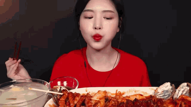 a woman is eating a large plate of food with chopsticks .