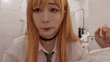 a girl with long blonde hair and a choker is making a funny face .