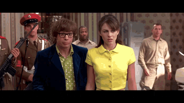 a woman in a yellow shirt is standing next to a man in a blue suit