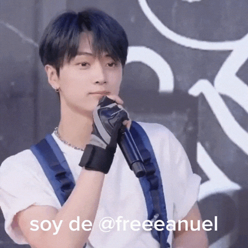 a young man holding a microphone with the words soy de @free anuel written below him