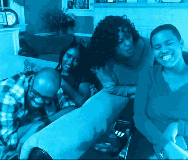 a group of people are sitting on a couch and smiling for a photo