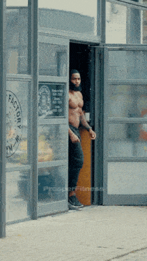 a shirtless man standing in front of a factory gym