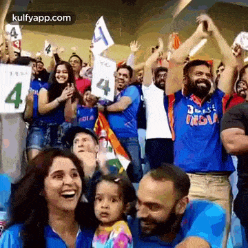 a group of people are sitting in a stadium holding up signs .