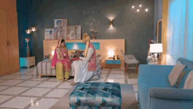 a man and a woman are sitting on a bed in a room