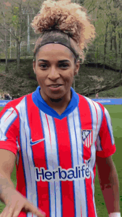 a woman wearing a red and white striped shirt with herbalife on it