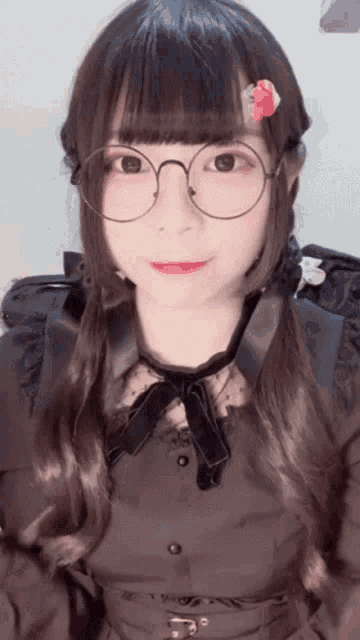 a girl wearing glasses and a black dress has a flower in her hair .
