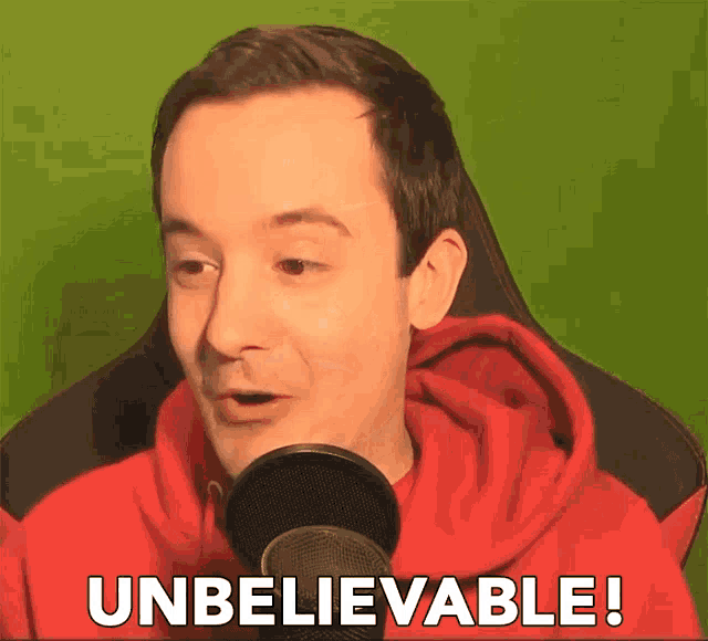 a man in a red hoodie is talking into a microphone and says unbelievable