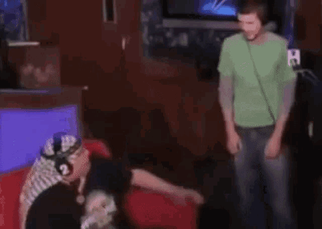a man in a green shirt is standing next to a woman wearing headphones and dancing .