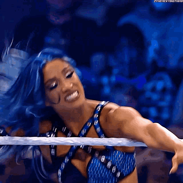 a woman with blue hair is in a wrestling ring and is smiling