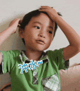 a young boy in a green shirt has a sticker on his shirt that says ' k '