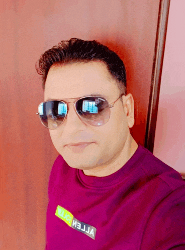 a man wearing sunglasses and a purple shirt with the word reliance on the front