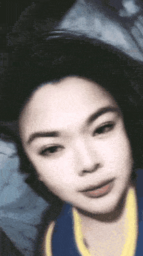 a close up of a woman 's face with a blue and yellow shirt