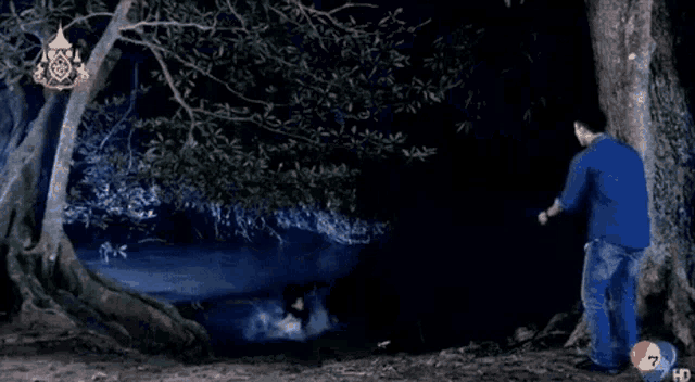 a man standing next to a tree in a dark forest