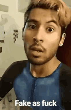 a man with a nose ring is making a funny face and the words fake as fuck are on the bottom