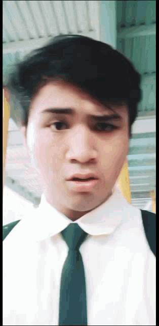 a young man wearing a white shirt and a green tie