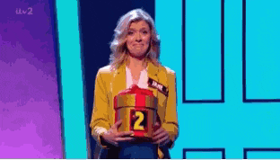 a woman in a yellow jacket is holding a box with the number two on it .