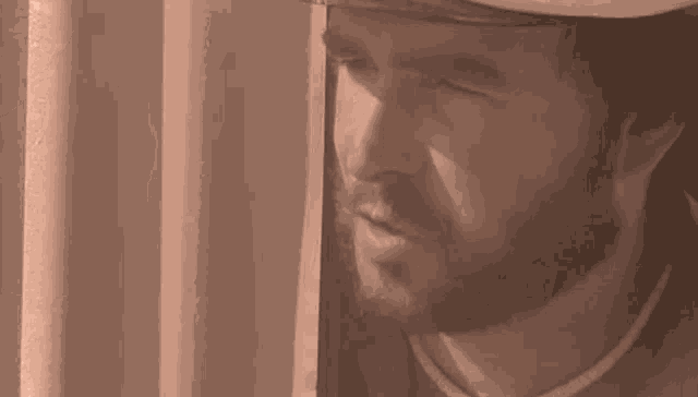 a man with a beard is looking out of a window with his mouth open .
