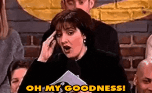 a woman is holding a microphone in front of a crowd of people and says oh my goodness .