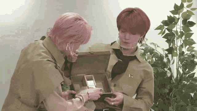 a man with pink hair is looking at a box
