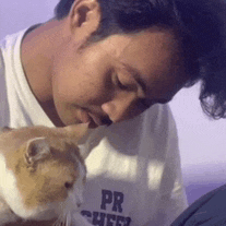 a man kissing a cat on the nose while wearing a shirt that says pr